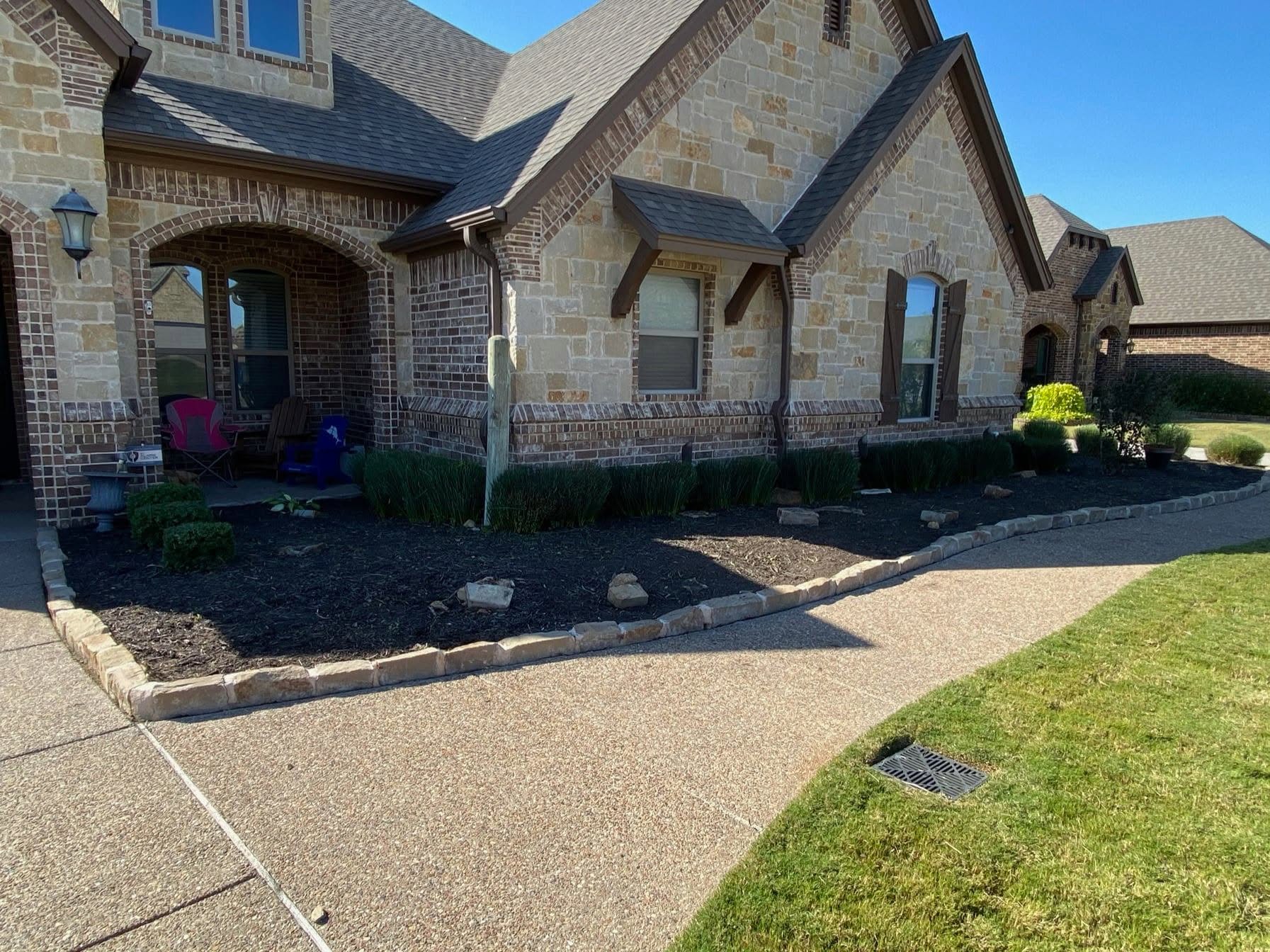 Front beds of a stone home before mulching and cleanup