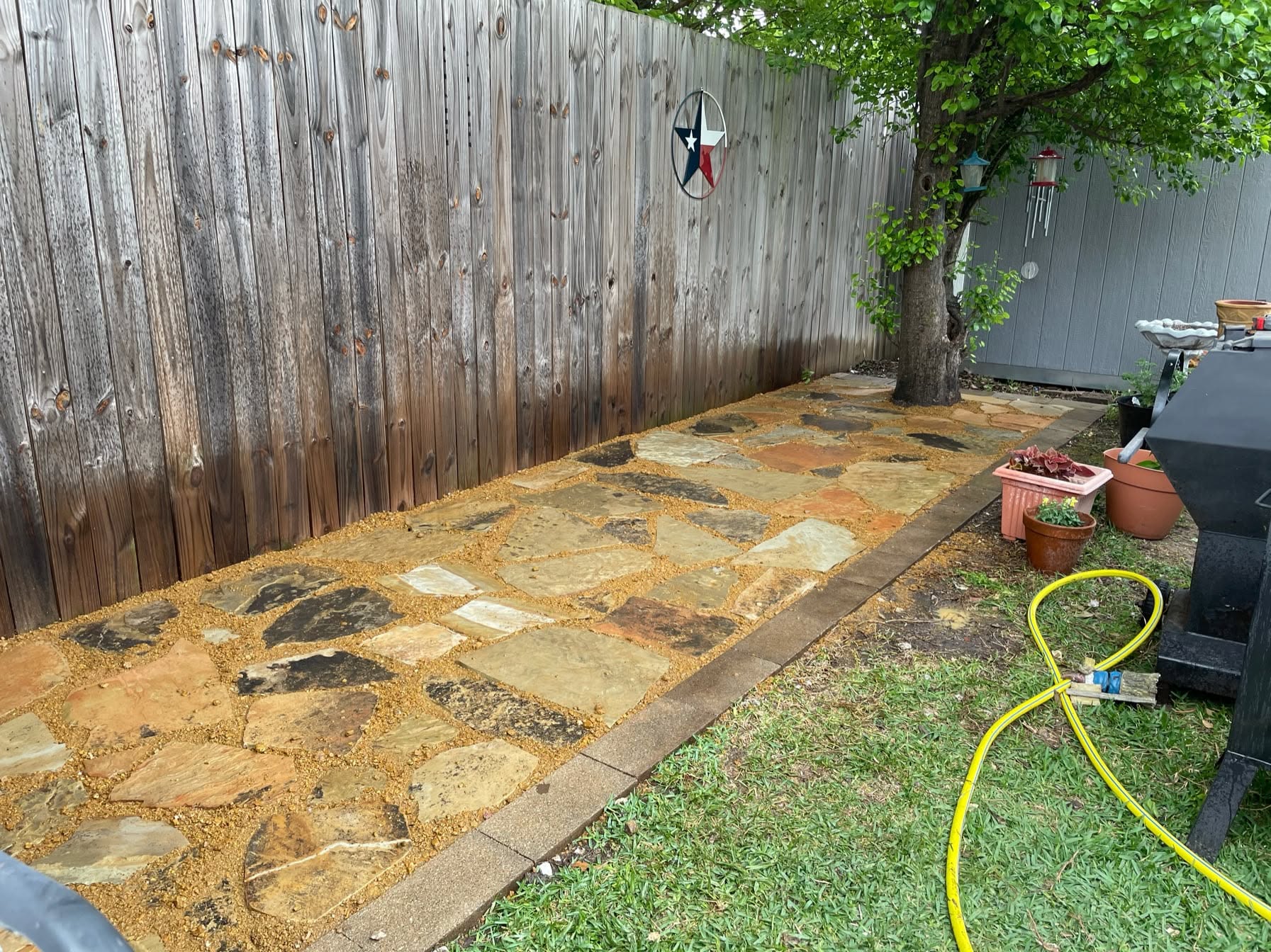 Finished flagstone walkway with decomposed granite joints along a backyard fence