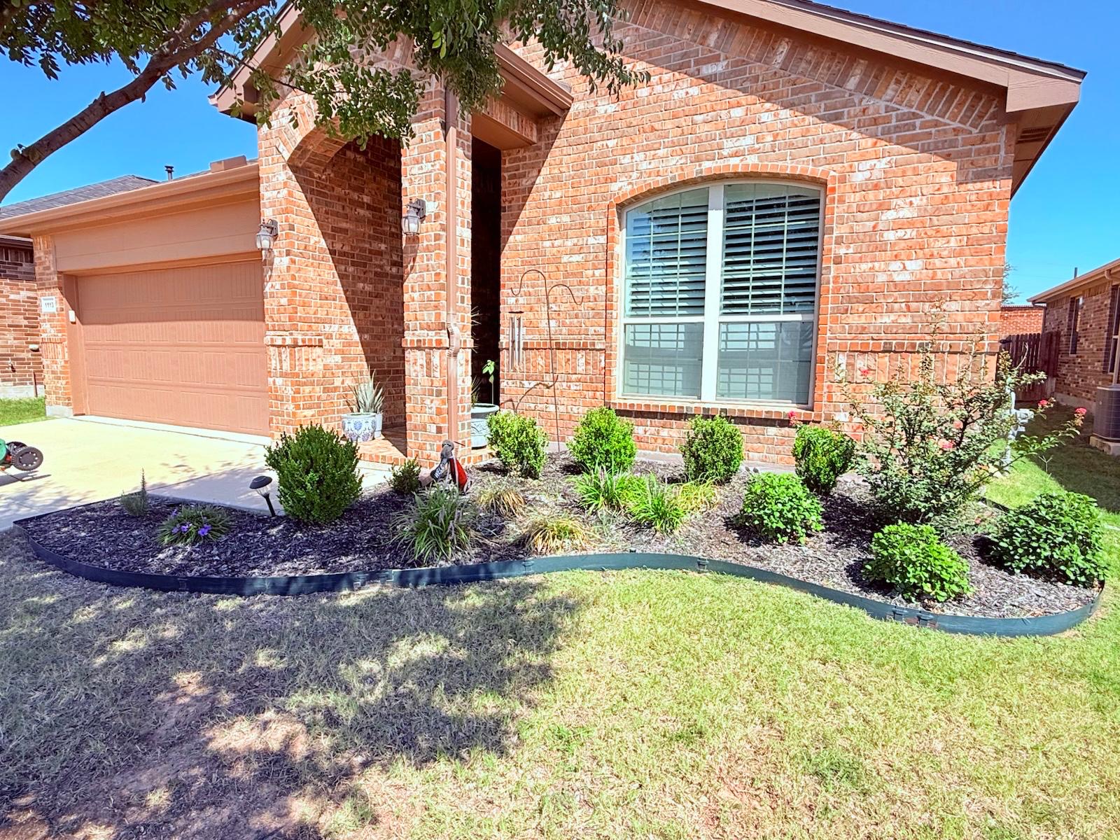 Residential front flower bed before its stone edging and mulch refresh