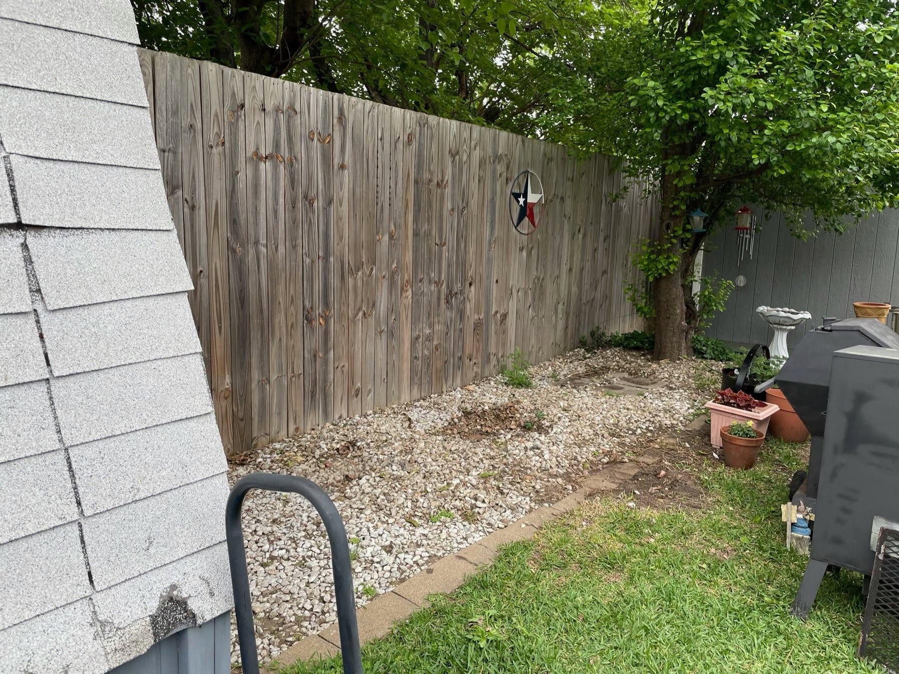 Backyard corner with gravel and weeds before walkway installation
