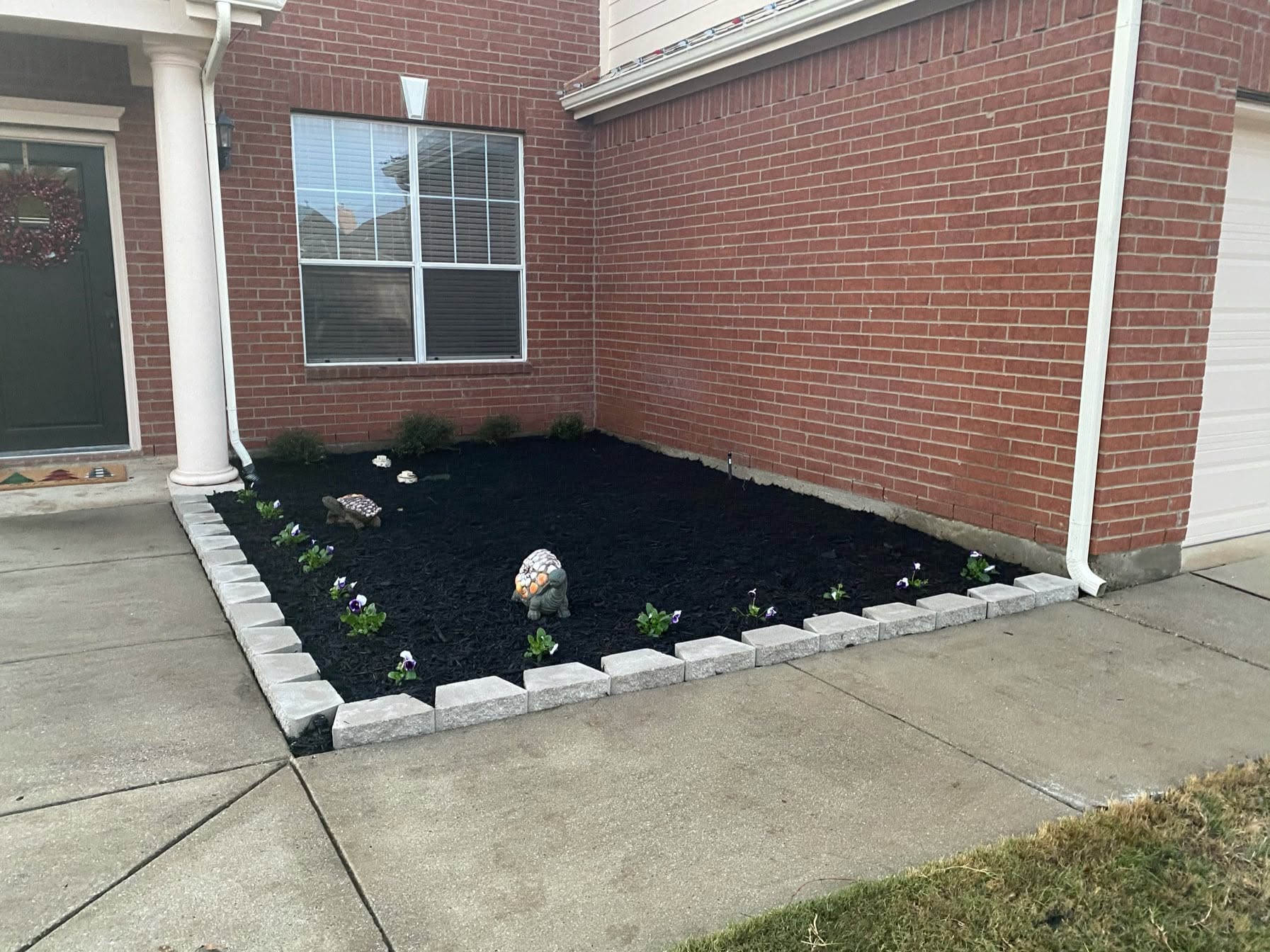 Finished front bed with stone edging, fresh mulch and seasonal flowers